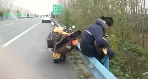 淡定文艺哥摩托车爆胎 竟坐在高速栏杆上弹吉
