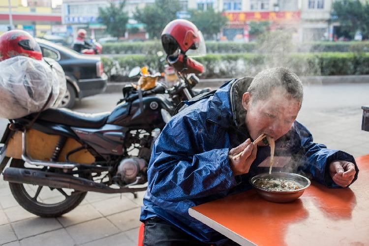 千里返乡的摩托大军：塑料纸绑腿胶带防风，骑行者路边烤火取暖